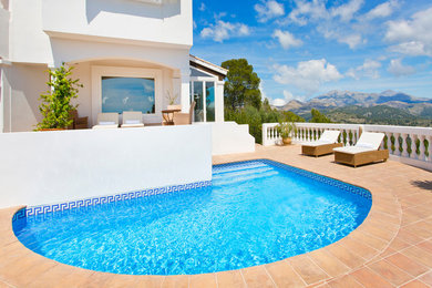 Immagine di una piscina mediterranea personalizzata dietro casa e di medie dimensioni con piastrelle