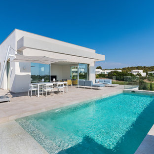 Modelo de piscina moderna, rectangular, en patio trasero, con suelo de baldosas