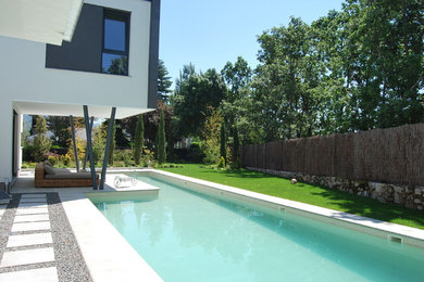 Imagen de casa de la piscina y piscina alargada moderna grande en forma de L en patio lateral con losas de hormigón