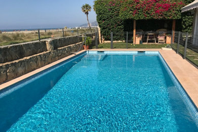 Diseño de piscina alargada mediterránea de tamaño medio rectangular en patio delantero