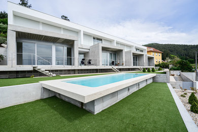 Ejemplo de piscina alargada minimalista grande rectangular en patio delantero con adoquines de piedra natural