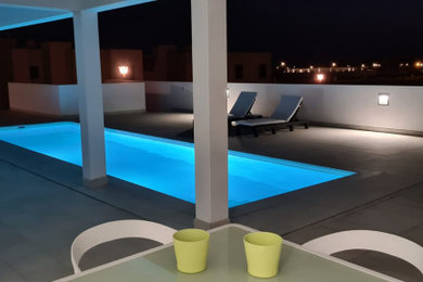 Modelo de piscina alargada minimalista de tamaño medio rectangular en patio lateral con suelo de baldosas