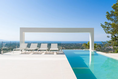 Foto de piscina infinita moderna rectangular en patio trasero con suelo de baldosas