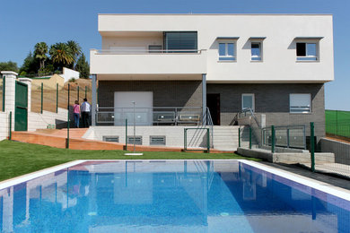 Modelo de casa de la piscina y piscina alargada actual de tamaño medio rectangular en patio delantero