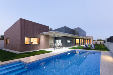 Modelo de casa de la piscina y piscina alargada actual de tamaño medio rectangular en patio trasero
