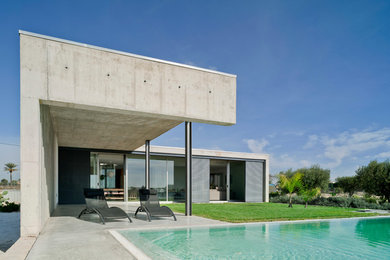 Ejemplo de casa de la piscina y piscina alargada contemporánea de tamaño medio rectangular en patio delantero con losas de hormigón