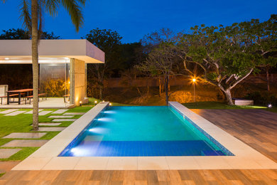 Modelo de casa de la piscina y piscina infinita actual de tamaño medio rectangular en patio trasero
