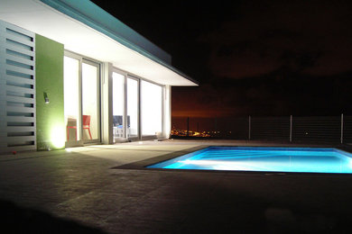 Imagen de piscina alargada minimalista pequeña rectangular en patio trasero con suelo de baldosas