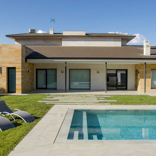 Diseño de piscina alargada, contemporánea, rectangular, en patio trasero, con suelo de baldosas