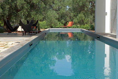 This is an example of a medium sized farmhouse back rectangular swimming pool in Bari with natural stone paving.