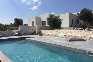 Ejemplo de piscina mediterránea rectangular en patio delantero con adoquines de hormigón