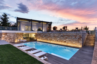 Immagine di una piscina monocorsia design rettangolare di medie dimensioni e dietro casa con pedane