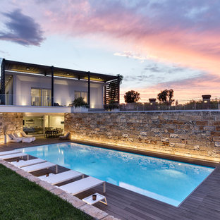 Immagine di una piscina monocorsia design rettangolare di medie dimensioni e dietro casa con pedane