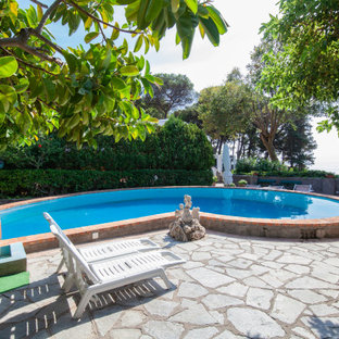 Esempio di una piscina mediterranea personalizzata con pavimentazioni in pietra naturale