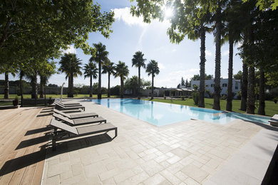 Ejemplo de piscinas y jacuzzis elevados mediterráneos grandes a medida en patio trasero con adoquines de piedra natural