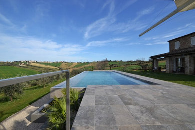 Immagine di una grande piscina a sfioro infinito contemporanea rettangolare con pavimentazioni in pietra naturale