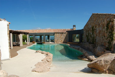 Ejemplo de casa de la piscina y piscina natural mediterránea grande a medida en patio con adoquines de piedra natural