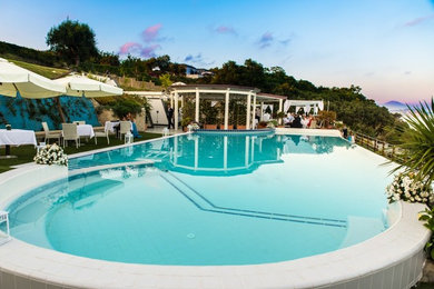 Esempio di una piscina a sfioro infinito mediterranea personalizzata di medie dimensioni con una dépendance a bordo piscina e piastrelle