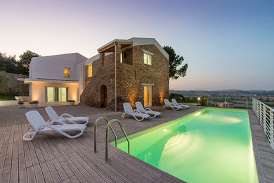 Inspiration pour une grande piscine latérale design rectangle avec une terrasse en bois.