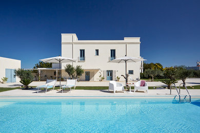 Modelo de piscina alargada mediterránea grande rectangular en patio trasero con losas de hormigón