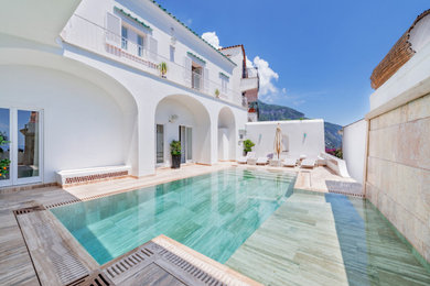 Immagine di una grande piscina a sfioro infinito minimal personalizzata in cortile con pavimentazioni in pietra naturale