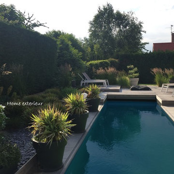 Abords d'une piscine avec plusieurs terrasses et massifs à Lesquin