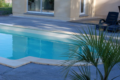 Réalisation d'une piscine design de taille moyenne et rectangle avec une dalle de béton.