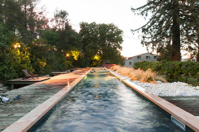 Idée de décoration pour un grand couloir de nage avant design sur mesure avec un bain bouillonnant et une terrasse en bois.