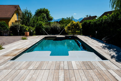 Exemple d'une piscine tendance rectangle avec une terrasse en bois.