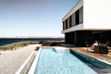 Idées déco pour une grande piscine arrière bord de mer rectangle avec une terrasse en bois.