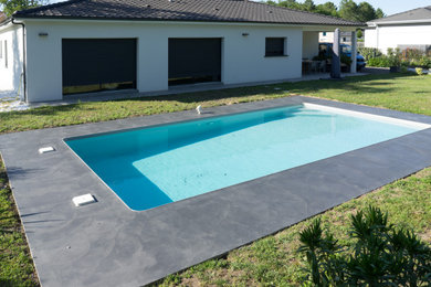 Modelo de piscina actual extra grande rectangular en patio con suelo de hormigón estampado