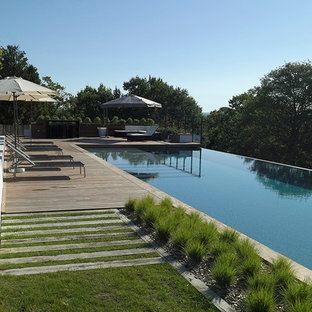 Esempio di un'ampia piscina a sfioro infinito minimalista rettangolare dietro casa con pedane