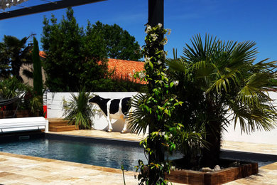 Réalisation d'un petit piscine avec aménagement paysager arrière méditerranéen en L avec des pavés en pierre naturelle.