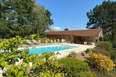 Ejemplo de casa de la piscina y piscina de estilo de casa de campo grande rectangular en patio trasero con entablado