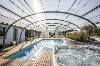 Esempio di una grande piscina design personalizzata dietro casa con pedane e una dépendance a bordo piscina