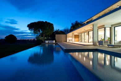 Imagen de piscina infinita contemporánea grande en forma de L en patio trasero