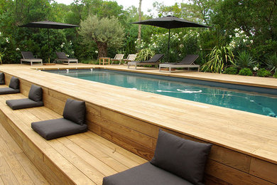 Cette image montre un grand couloir de nage design rectangle avec une terrasse en bois.