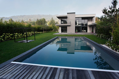Modelo de piscina moderna de tamaño medio rectangular en patio con entablado