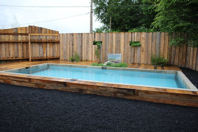 Réalisation d'une piscine minimaliste de taille moyenne avec un point d'eau et une terrasse en bois.