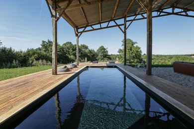 Idée de décoration pour une grande piscine arrière champêtre rectangle avec une terrasse en bois.