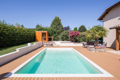 Réalisation d'une grande piscine minimaliste rectangle avec une terrasse en bois.