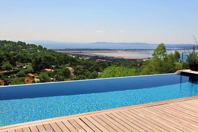 Cette photo montre une grande piscine à débordement tendance rectangle avec une terrasse en bois.
