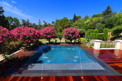 Réalisation d'une piscine design de taille moyenne et rectangle avec une terrasse en bois.