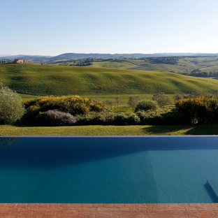 Immagine di una piscina a sfioro infinito moderna rettangolare dietro casa con pavimentazioni in mattoni