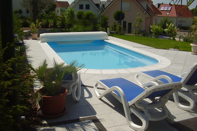 Foto de casa de la piscina y piscina alargada actual de tamaño medio rectangular en patio trasero con losas de hormigón