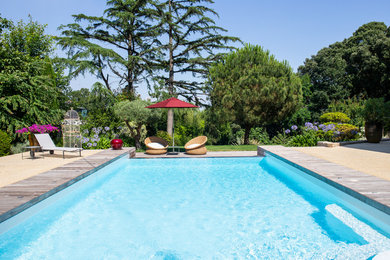 Idée de décoration pour une grande piscine arrière et à débordement tradition sur mesure avec une terrasse en bois.