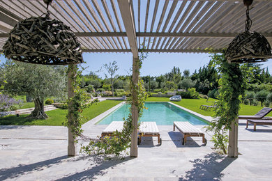 Ejemplo de piscina campestre extra grande rectangular en patio trasero con suelo de baldosas