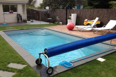 Cette photo montre une piscine arrière tendance de taille moyenne et rectangle avec une terrasse en bois.