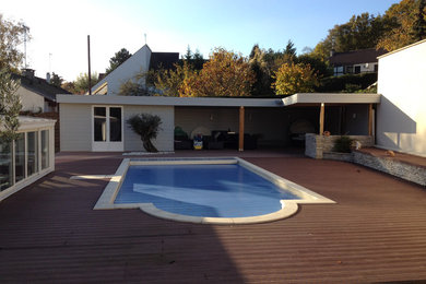 Diseño de piscina actual grande en patio trasero con entablado