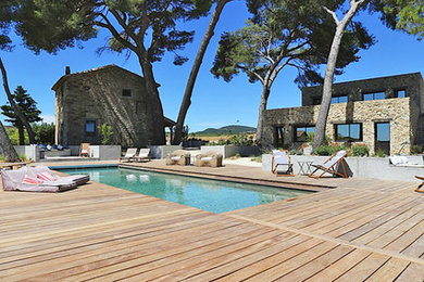 Aménagement d'une piscine méditerranéenne avec une terrasse en bois.